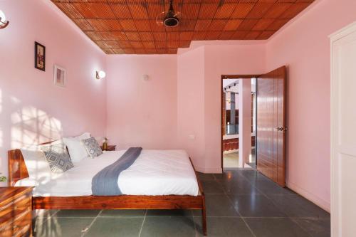 a bedroom with a bed with pink walls and a wooden ceiling at The Rustic Ridge Villa by StayJadePool1hr E-city in Denkanikottai