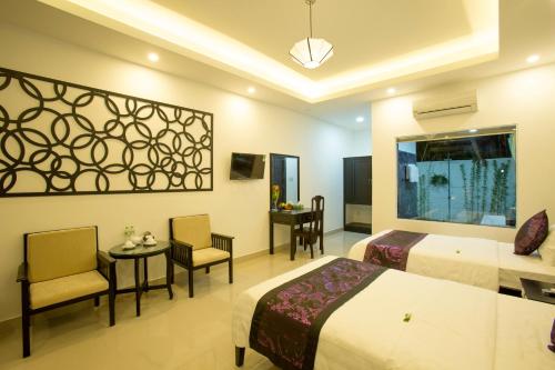 Habitación de hotel con 2 camas, mesa y sillas en Hoi An Hideaway Villa, en Hoi An