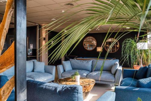 eine Lobby mit blauen Sofas, einem Tisch und Pflanzen in der Unterkunft Hotel Ignacio - PalomarGroup in Chiva