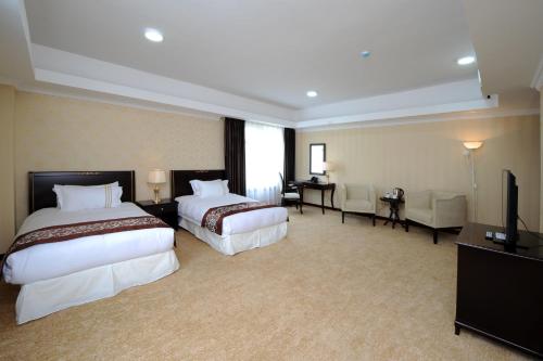 a hotel room with two beds and a television at Alpha Hotel Ulaanbaatar in Ulaanbaatar