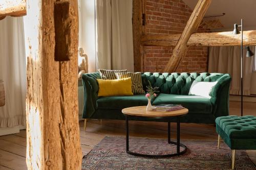 a living room with a green couch and a table at Gut Pohnstorf in Alt Sührkow