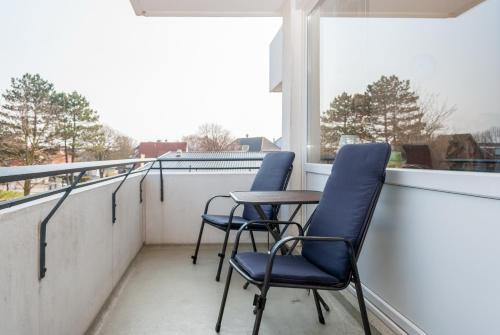 a balcony with two chairs and a table and a window at Hanseatic 210 in Duhnen
