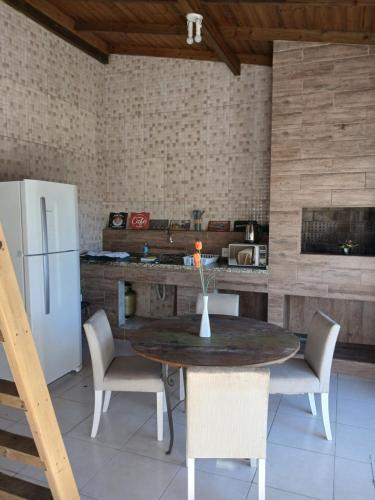 a kitchen with a table and chairs and a refrigerator at Loft e casa Catarina in Imbituba