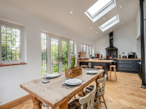 a kitchen with a wooden table and some windows at Mill House in Lowestoft