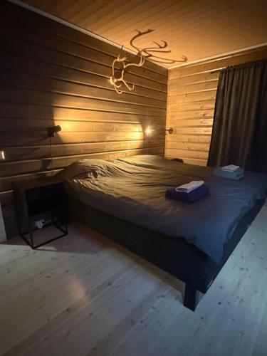 a bedroom with a bed in a wooden wall at ReindeerCabin PoroMökki LEVI in Kittilä