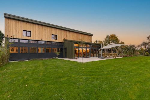 a large building with a green lawn in front of it at Dragons Barn with Hot Tub in Great Malvern