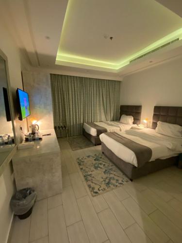 a hotel room with two beds and a television at Gardenia Park Quraish hotelفندق جاردينا بارك قريش in Jeddah