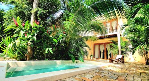a swimming pool in front of a house with trees at YAM HOTEL in Mazunte
