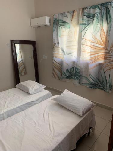 two beds in a room with a mirror and a painting at Casa em Praia Formosa in Cabedelo