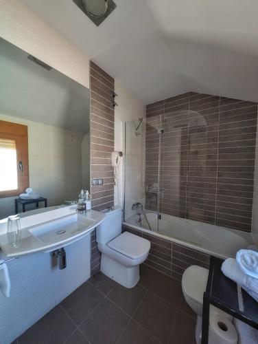 a bathroom with a toilet and a tub and a sink at Hotel Anabel Baza in Baza