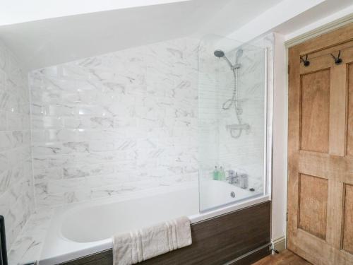 a white bath tub in a bathroom with a stone wall at Joy's Cottage in King's Lynn