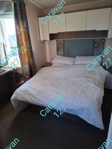 a large white bed in a bedroom with a window at Caravan 127 in Barmouth