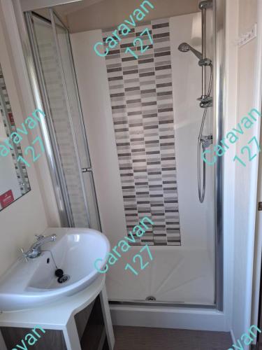 a bathroom with a white sink and a shower at Caravan 127 in Barmouth
