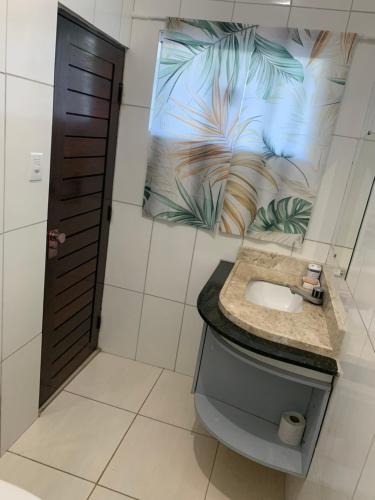 a bathroom with a sink and a poster on the wall at Casa em Praia Formosa in Cabedelo