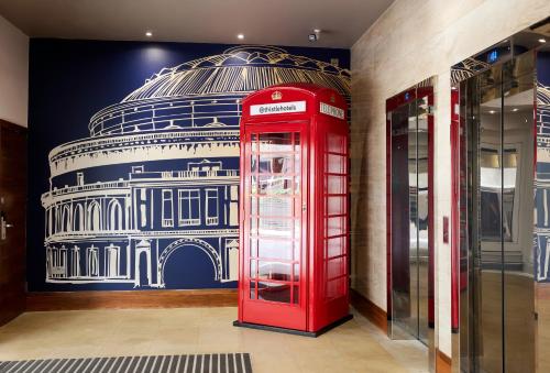 a red phone booth in a room with a building at Thistle London Hyde Park Kensington Gardens in London