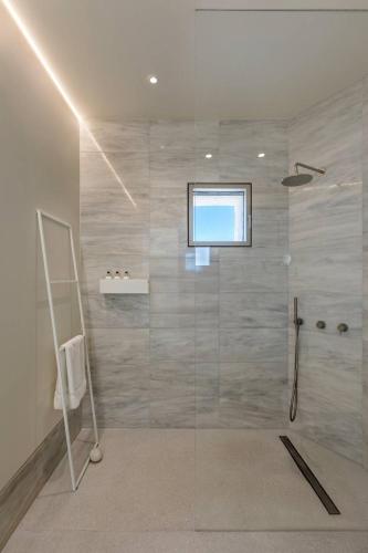 a bathroom with a glass shower with a window at MedBlu Paros in Paros National Airport