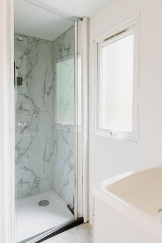a white bathroom with a shower and a tub and a window at The Red Shutter Cottage in Hattemerbroek
