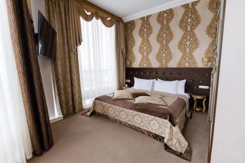 a bedroom with a bed and a tv and curtains at Boutique Spa Casino Hotel Lybid Plaza in Khmelnytskyi