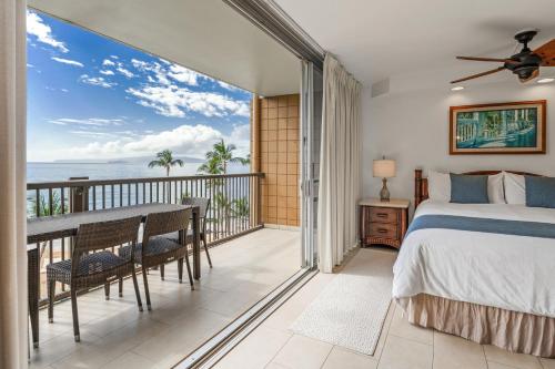 a bedroom with a bed and a balcony with the ocean at Mana Kai 611C in Wailea