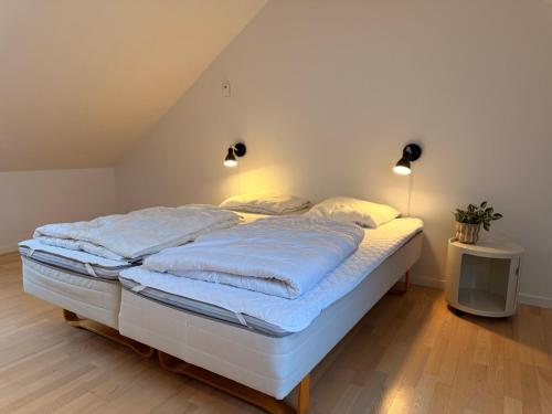 a bedroom with a bed with blue sheets and lights at Plesners Havnelejligheder in Skagen