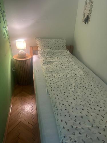 a bed in a room with a lamp on a table at Apartman Miškec in Kupres