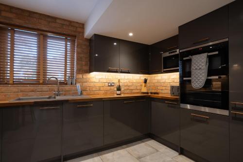 a kitchen with black cabinets and a brick wall at The Old Pitman's house in Ollerton