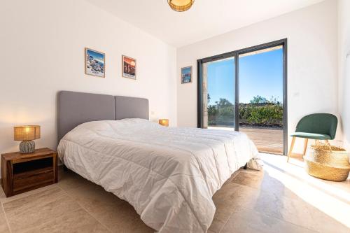 a bedroom with a bed and a large window at Villa U Capu - Piscine Privée in Lecci