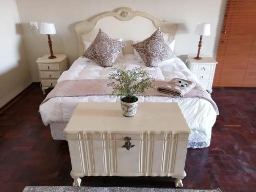 a bedroom with a white bed with a table at Shelanti Game Reserve in Marken
