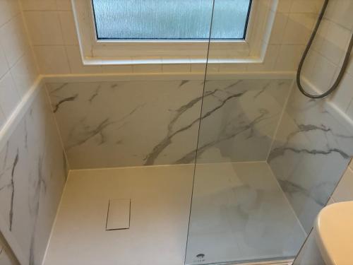 a bathroom with a shower with white marble at Kerenza Cottage - Families & Pets in Uny Lelant