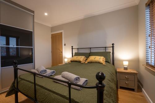 a bedroom with a bed with green sheets and pillows at The Old Pitman's house in Ollerton