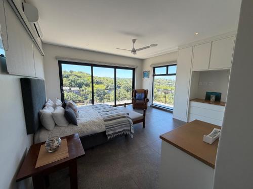 a bedroom with a bed and a large window at Parrotfish Room in Ballito
