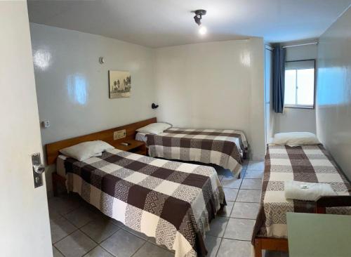 a hotel room with two beds and a window at Hotel e Restaurante Samburá in Olinda