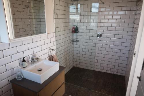 a white bathroom with a sink and a shower at Parrotfish Room in Ballito