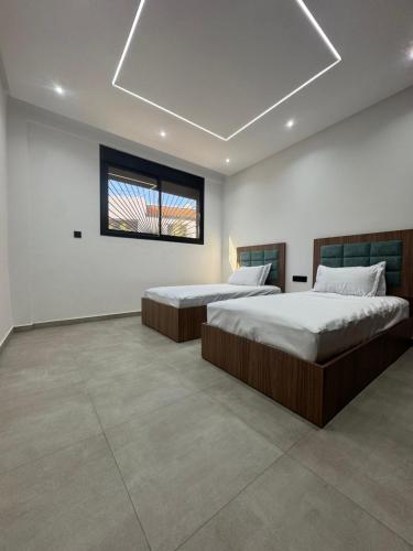two beds in a large room with a window at Appartement sur villa in Temara