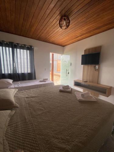 a large bedroom with two beds and a wooden ceiling at Suítes Taipu de Fora in Marau
