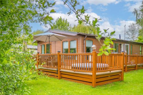 a wooden house with a large deck with an umbrella at Looby Lodge in Tattershall