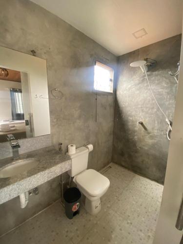 a bathroom with a toilet and a sink and a mirror at Suítes Taipu de Fora in Marau