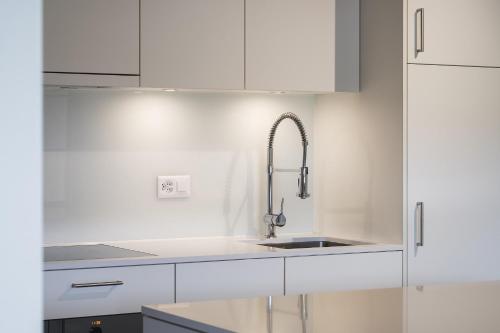 a kitchen with white cabinets and a sink at Hotel Mulin by Amanthos in Breil/Brigels