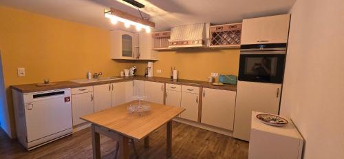a kitchen with white appliances and a wooden table at La Maison Ôtrement in Martelange