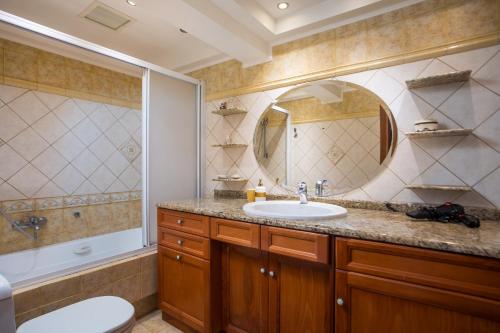 a bathroom with a sink and a toilet and a mirror at Christine Beachside Villa Pefkos in Pefki