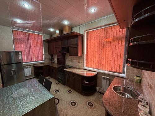 a kitchen with brown cabinets and a sink and two windows at The Skyline Apartments in Samarkand