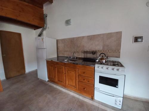a kitchen with a white stove and a refrigerator at Complejo Maylen Meliquina in Lago Meliquina