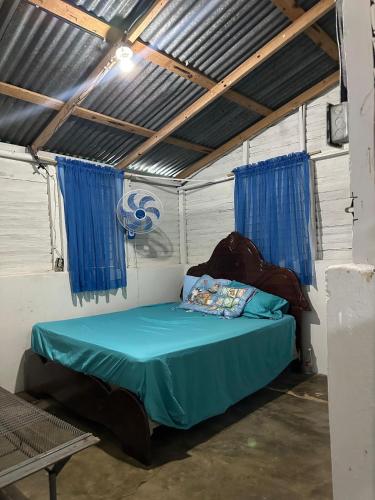 a bedroom with a bed with blue sheets and blue curtains at Casa de Campo Vive in Ensanche Savica de Mendoza
