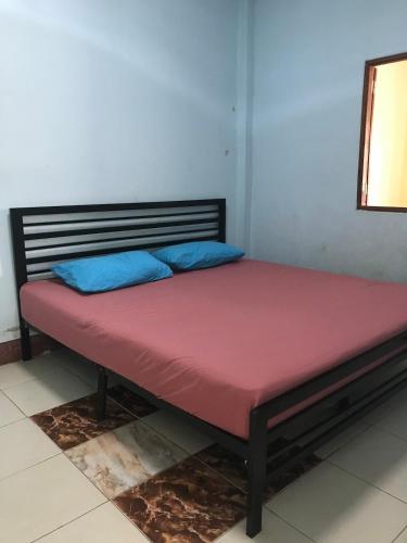a bed with a red mattress and blue pillows on it at Yada House in Nong Ki