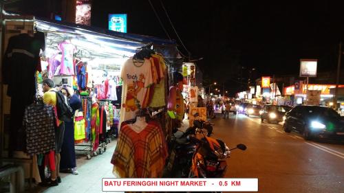 a crowd of people standing on a city street at night at By the Sea- Pool and Sea View in Batu Ferringhi