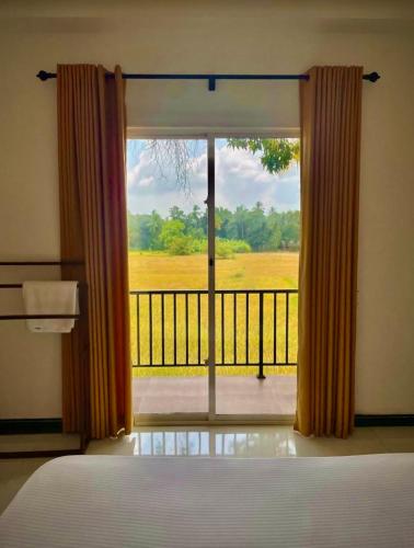 a bedroom with a window with a view of a balcony at Man Guest Polonnaruwa in Polonnaruwa