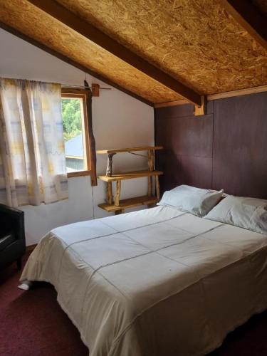 a bedroom with a large white bed with a window at Cabaña Cielo Patagonico in Futaleufú