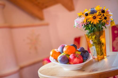 eine Vase mit Blumen und eine Schale mit Obst auf dem Tisch in der Unterkunft Hotel Tolderhof in Innichen