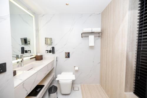 a white bathroom with a toilet and a sink at 7Crown Tahliah Hotel in Riyadh