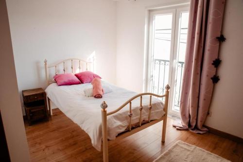 a bedroom with a bed with pink pillows and a window at Casa da avo Rita in Pêro Viseu